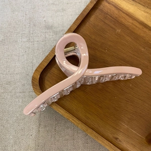 Close-up of a large pink ice-glaze crossover hair claw clip on a wooden tray detail