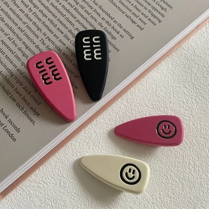Set di fermagli per capelli colorati con faccina sorridente e logo su un libro