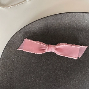 Gros plan d'une barrette à cheveux nœud rose avec texture côtelée et bords en dentelle
