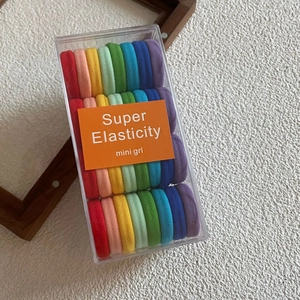Close-up of vibrant elastic hair ties in a clear box with rainbow candy colors