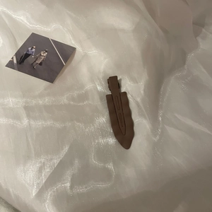 Detailed view of coffee brown wave hair clip on white fabric with vintage photo decor