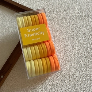 Detail of warm-toned elastic hair ties in a transparent box for secure storage