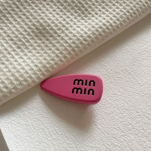Dettaglio del fermaglio fucsia opaco con logo min min su tessuto a nido d'ape