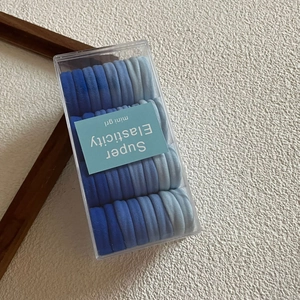 Detail of multi-shade blue elastic hair ties neatly organized in a clear plastic box