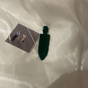 Detail of dark green matte wave hair clip on a white pleated fabric background