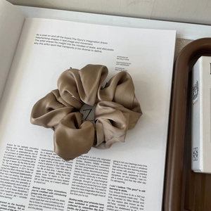 Detailed texture of a large champagne silk scrunchie on a stylish fashion magazine