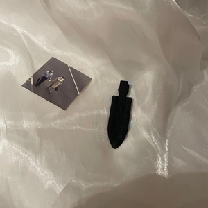 Close-up of matte black leaf-shaped hair clip on white silk fabric background