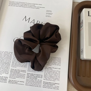 Detailed view of dark brown satin scrunchie with silk luster on a fashion magazine