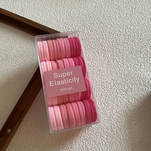 Macro shot of high-elasticity hair ties set in pink gradient shades within a clear box