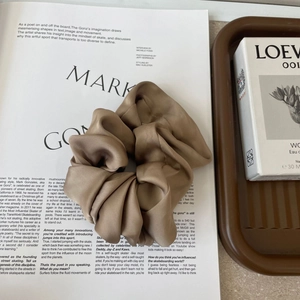 Macro detail of dark coffee silk satin scrunchie with elegant folds and glossy finish