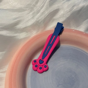 Gros plan sur la barrette patte de chat rose et bleue sur tissu de soie blanc