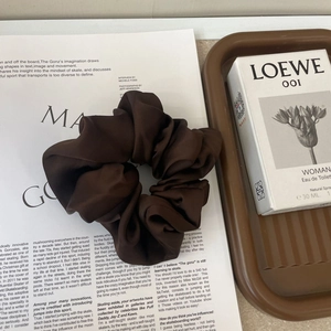 Close-up of a brown satin silk scrunchie on a stylish magazine with warm tones