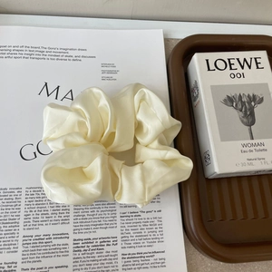 Close-up of cream large satin scrunchie with silky texture on a lifestyle background