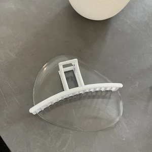 Detail of a large white acrylic shark hair clip with a minimalist geometric hollow design