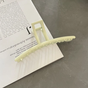 Matte light green oversized metal shark hair claw clip shown on a vintage book