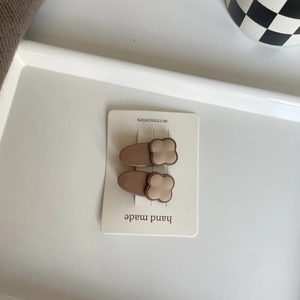 Two-piece set of matte brown and beige bear-themed hair clips on a display card