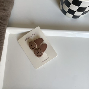 Set of two brown matte smiley face hair clips on card for Korean style minimalist hair styling