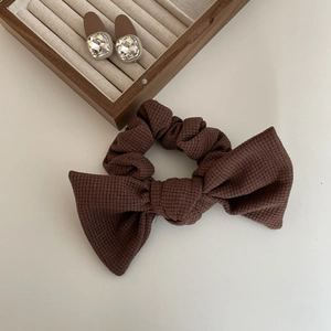 Detail of dark brown waffle fabric bow scrunchie and clear gemstone earrings set