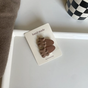 Detail view of two cute 3D brown bear hair clips on a white handmade display card
