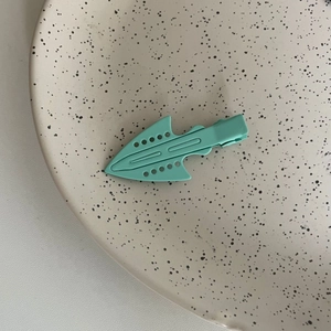 Close-up of mint green matte arrow-shaped hair clip with circular hollow design