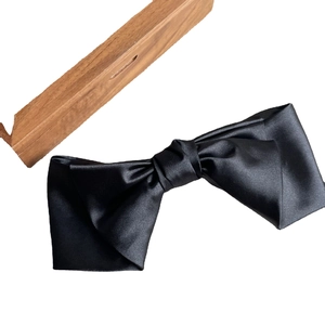 Elegant large black satin silk bow hair clip with smooth glossy finish on white background
