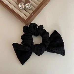 Elegant black waffle texture bow hair scrunchie with jewelry decor in minimalist setting
