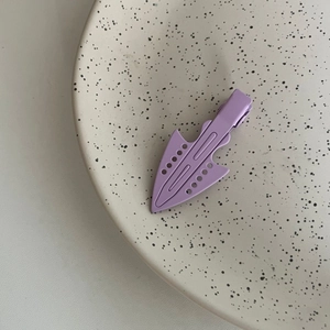 Detailed macro view of lavender purple matte metal hair clip on a ceramic dish