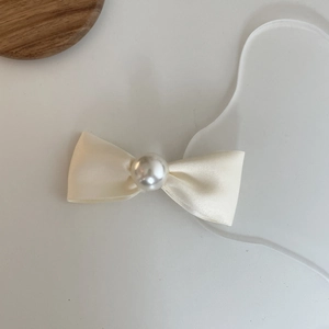 Elegant cream satin bow hair clip with a central white pearl ornament on a white base