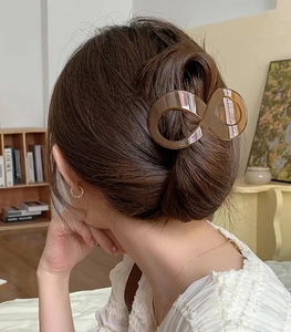 Vue arrière d'un mannequin portant une pince à cheveux ambre en forme d'infini pour chignon