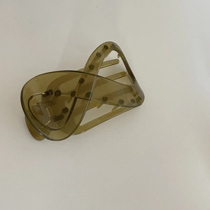 Détail d'une pince à cheveux vert olive ondulée avec décoration de points noirs