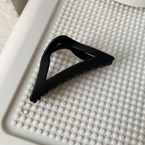 Close-up of matte black triangle hair claw clip with serrated teeth and metal spring