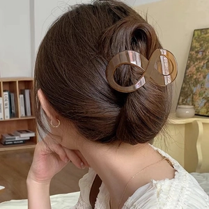 Pince à cheveux ambre élégante en forme d'infini portée par une femme dans un cadre chaleureux