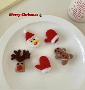 Dettaglio di cinque graziose mollette natalizie in feltro con Babbo Natale e renna in un piatto