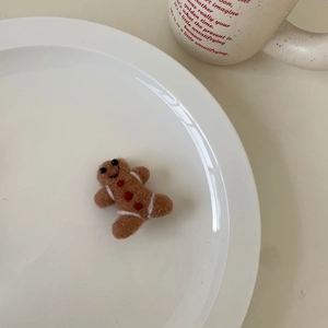 Graziosa clip per capelli in feltro a forma di omino di pan di zenzero su un piatto