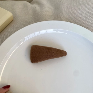 Detail view of a brown velvet triangle hair clip on a white decorative ceramic plate