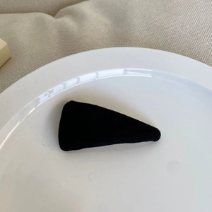 Detailed view of a black velvet triangle hair clip showing soft flocked texture and finish