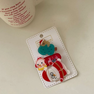 Close-up of Christmas hair clips with Santa Claus and brown bear on festive card