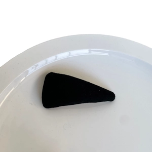 Minimalist black velvet triangular BB hair clip for women on white ceramic plate