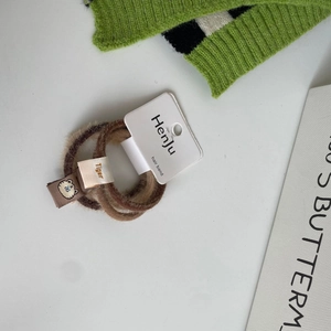 Detailed macro view of plush hair ties with cute bear embroidery and tiger letter labels