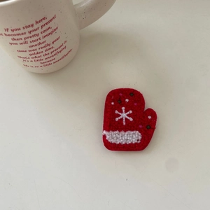 Detail shot of red felt glove hair clip with white snowflake pattern for Christmas