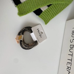 Detail of Korean leopard print plush hair tie with cartoon bear tag on display card