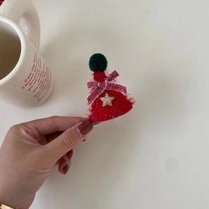 Close-up of a festive Christmas mini hat hair clip with red plush and stripe bow detail