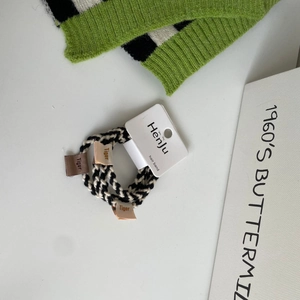 Detail of three black and white woven hair ties with Tiger cloth labels on a display card
