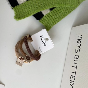 Detailed view of three plush fur hair ties in brown tones with cute bear patch labels