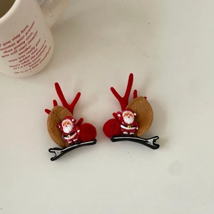 Detail of Christmas reindeer antler hair clips with Santa Claus motifs and red pom-poms