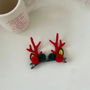 Close-up of festive Christmas reindeer antler hair clips with plush pom-poms and metal base
