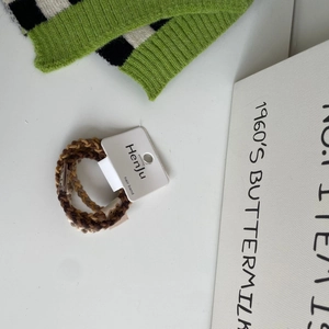 Close-up of woven elastic hair bands in brown and beige tones with a branded tag