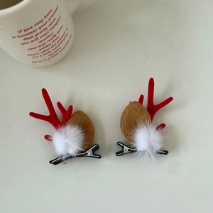 Close-up of Christmas reindeer antler hair clips with plush pom-poms on duckbill clips