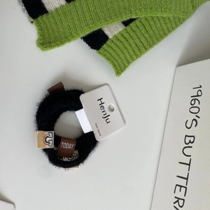 Set of 4 soft black plush hair scrunchies with cute woven labels on white background