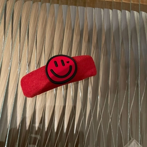 Nahaufnahme von rotem Plüsch-Haarschmuck mit niedlichem Herz-Auge-Smiley-Abzeichen